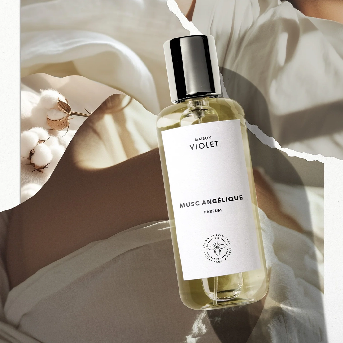 Artistic display of Musc Angélique perfume by Maison Violet surrounded by soft cotton and delicate fabrics.
